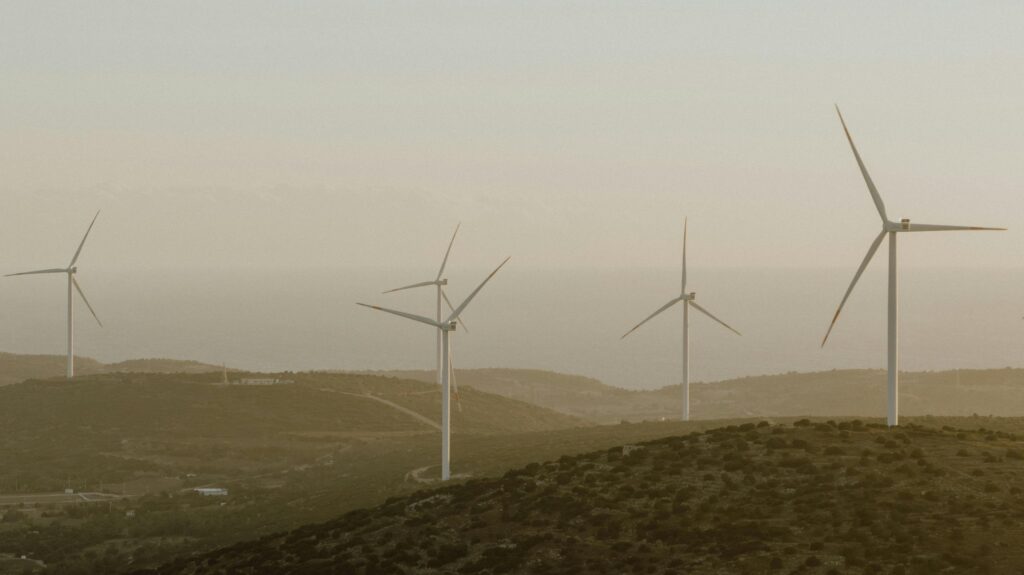 Wind turbines on hills with sea in background, captured in Çeşme, Türkiye.